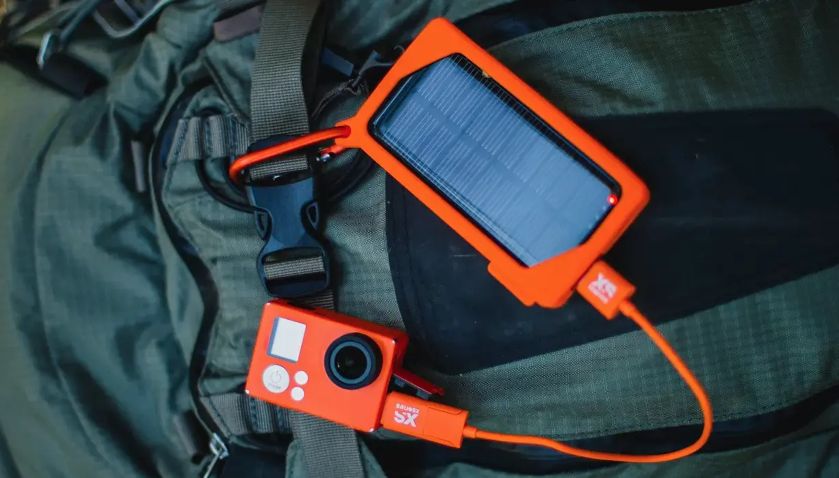 Outdoor pictures of the XSories XSolar Charger hooked to a bag and recharging under the sun with a solar charger and power bank with solar panel