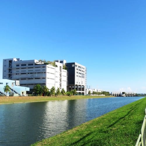 photography of a factory in Asia where Datact manufacture product and packaging for clients. This image has the factrory from outside, blue sky and a river along the road.
